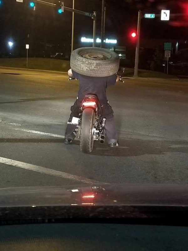 a guy ridding his bike with tire on his head
