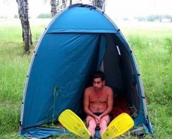 a man with flippers sitting lonely in a tent 